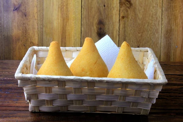 Coxinha na cesta, lanches tradicionais da culinária brasileira recheados com frango, isolados em mesa de madeira rústica — Fotografia de Stock