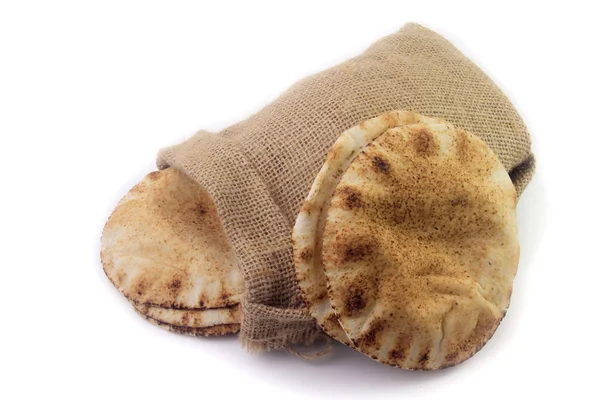 Pan de pita aislado sobre fondo blanco de bolsa de tela rústica. Comida de la cocina árabe — Foto de Stock