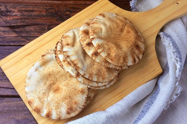 Πίτα που απομονώνεται σε ξύλινη σπάτουλα που βγαίνει από το φούρνο. Παραδοσιακό φαγητό Αραβικής κουζίνας — Φωτογραφία Αρχείου