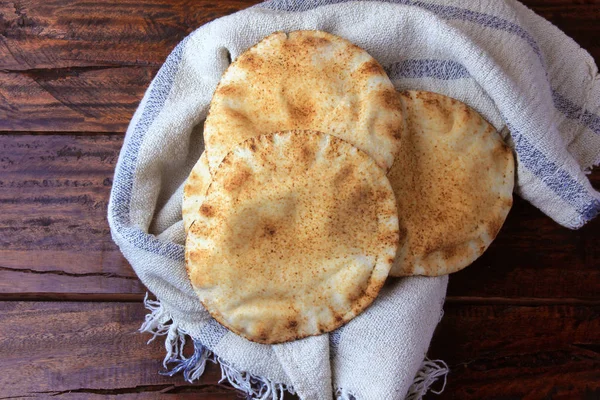 Η πίτα απομονώνεται σε ρουστίκ ξύλινο τραπέζι σε ρουστίκ ύφασμα. Παραδοσιακό φαγητό Αραβικής κουζίνας — Φωτογραφία Αρχείου