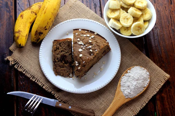 Domácí banánový dort vyrobený z ovesné kaše na rustikálním dřevěném stole. bez cukru, bez mléka, bez lepku — Stock fotografie