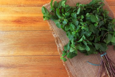 Rustik ahşap masada taze organik yeşil nane grubu. Şifalı ve mutfak kullanımları ile aromatik nane
