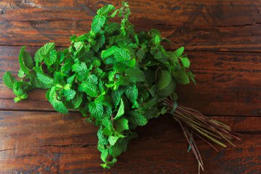 Rustik ahşap masada taze organik yeşil nane grubu. Şifalı ve mutfak kullanımları ile aromatik nane