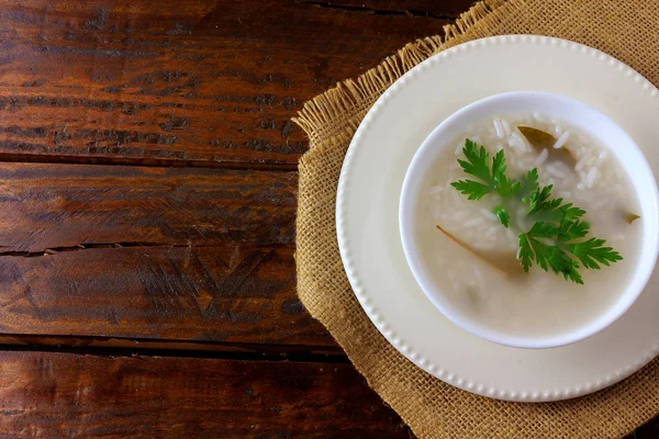 素朴な木製のテーブルのセラミックボウル、アジア料理の典型的なお粥 — ストック写真