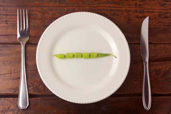 Pojęcie ograniczenia kaloryczności. Ścisła dieta. Mała wiązka amerykańskich brokułów na białym naczyniu z widelcem i nożem — Zdjęcie stockowe