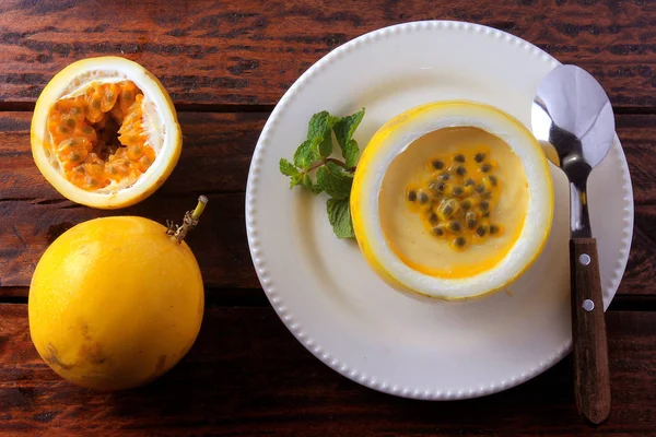 Postre Mousse de maracuyá en la cáscara de la fruta, en plato sobre mesa de madera rústica — Foto de Stock