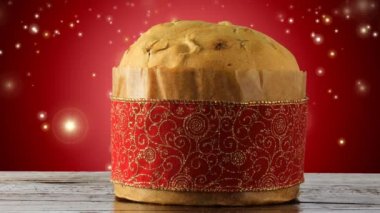 İtalyan panettonu süslemeli noel masası, kırmızı arka plan parlayan ışık parçacıkları, kayan yıldızlar