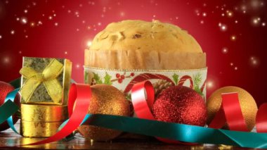 İtalyan panettonu süslemeli noel masası, kırmızı arka plan parlayan ışık parçacıkları, kayan yıldızlar