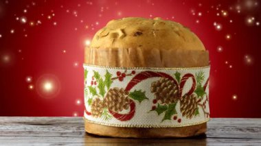 İtalyan panettonu süslemeli noel masası, kırmızı arka plan parlayan ışık parçacıkları, kayan yıldızlar
