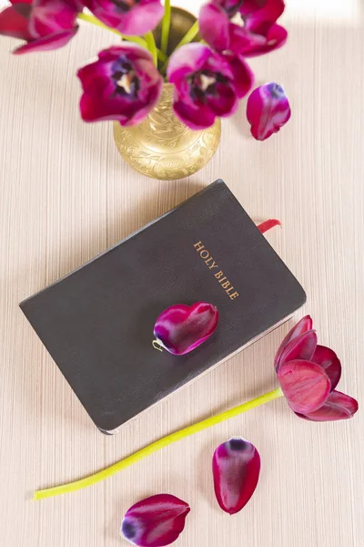 Holy Bible with flowers on wooden table background.