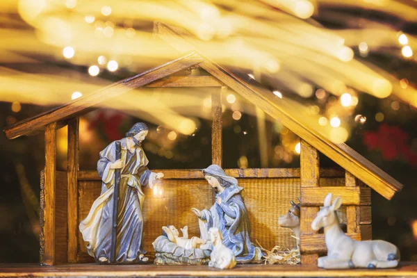 Christmas Manger scene with figurines including Jesus, Mary, Joseph and sheep. Focus on mother! Lights trail in front of camera.