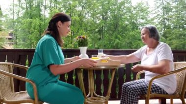 Gülümseyen genç hemşire Hemşirelik evde mutlu kadın kıdemli için kahvaltı servisi Pan. Yavaş hareket 4k