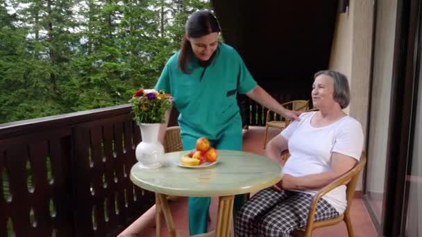 笑顔の高齢女性のパンは 特別養護老人ホーム ケアセンターで彼女の援助と過ごす時間に座る スローモーション — ストック動画