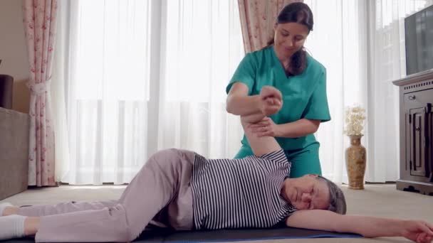手臂受伤后在物理治疗师康复期间的高级 老年妇女正在由物理治疗师在家里或护理中心康复 慢动作4K 手持式运动 — 图库视频影像