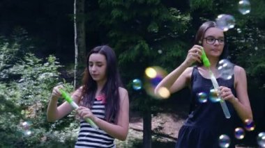 Genç kızlar eğlenmek ve oyun yaz süresi içinde sabun köpüğü üfleme. Yavaş hareket 4k el hareketi