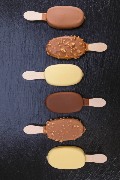 冰激凌在棍子上覆盖着巧克力在黑色石板 — 图库照片