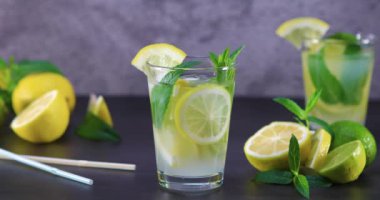 Gri ve siyah arka planda bir cam nane ile ev yapımı ferahlatıcı yaz limonata. Dolly 4k vurdu