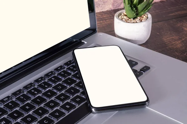 Smartphone s prázdnou bílou obrazovkou na klávesnici přenosného počítače — Stock fotografie