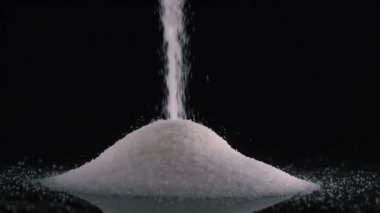 Siyah arkaplana 180fps yavaş çekimde beyaz şeker dökülüyor.