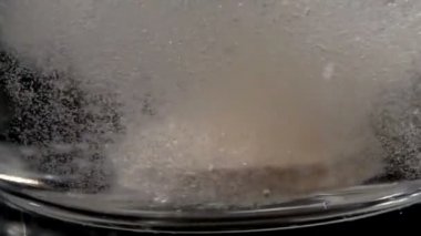 Siyah arkaplandaki bir bardak suya düşen coşkun tabletin yakın çekimi. İlaç konsepti alıyorum. Sağlıklı bir hayat için kalsiyum, magnezyum, vitamin ve aspirin alıyorum. 180fps 'de yavaş çekim..