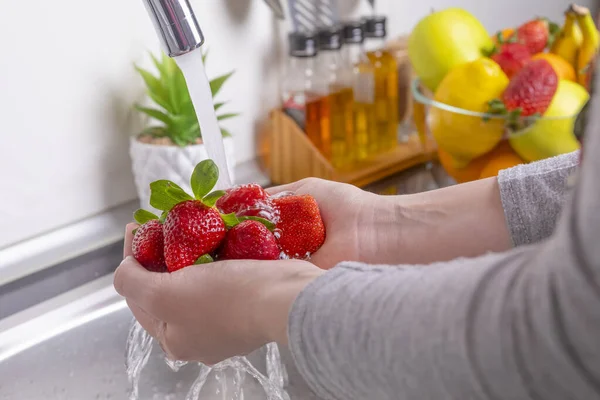 台所でイチゴを洗う女性の手 新鮮で健康的な果物の概念を食べる — ストック写真