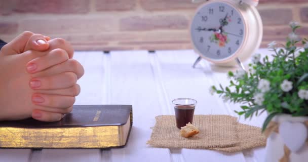 聖書を読んで聖餐式を取る若い女性 聖書とイエス キリストの血と体のワインとパンのシンボル ガラスに集中しろ クローズアップドリーショット4K — ストック動画