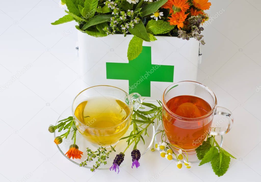Herbal Medicine. Rosemary, mint, chamomile, thyme, melissa, lavender and calendula in a first aid box. Two glass cups of infusions in foreground.