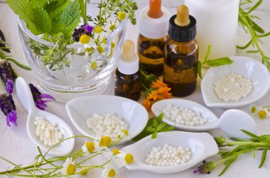 Alternative Medicine. Homeopathy. Globules, essential oils and fresh herbs on white background. clipart