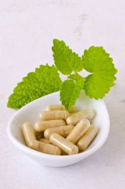 Alternatif Tıp. Bitkisel tedavi. Melissa veya melisa kapsül. Beyaz arka plan.