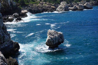 Denizin tabanında dalgalar tarafından Kazıklı, tek başına bir taşla görüntüleyin. İspanya, ada Mallorca, yaz, Haziran 2018 