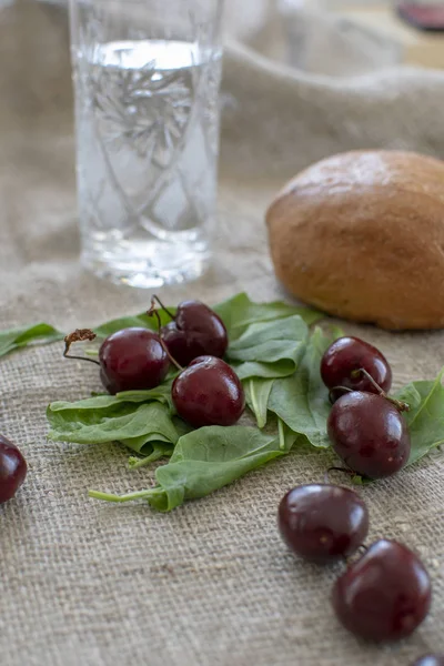 Yaban mersini masaya dağınık, tuval masa örtüsü, yeşiller, arka planda bir cam ve bir chaubatha