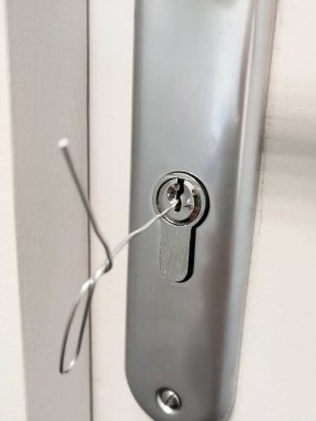 Small metal wire inserted in the keyhole of the door for unlocking doors without key clipart