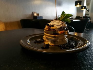 Koyu ahşap restoran masada yaban mersini ile Amerikan yığın krep