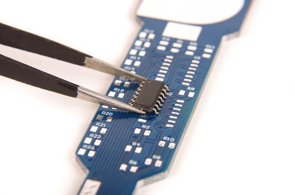 Small electronics integrated circuit IC on empty printed circuit board ready for hand assembly