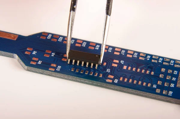 Small electronics integrated circuit IC on empty printed circuit board ready for hand assembly