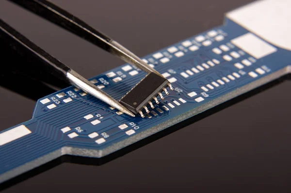 Small electronics integrated circuit IC on empty printed circuit board ready for hand assembly