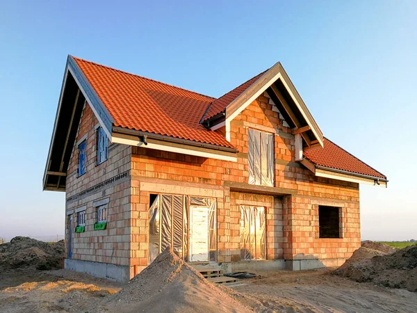 Modern house constructions. Half finished house with roof during evening