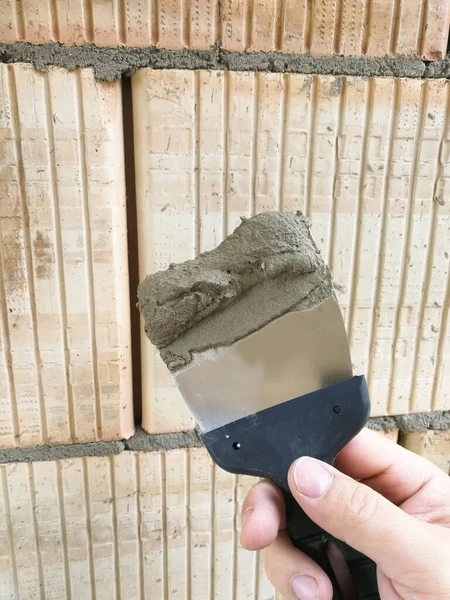 建設現場で接着剤でタッピングナイフツールを保持する建設労働者の手 — ストック写真