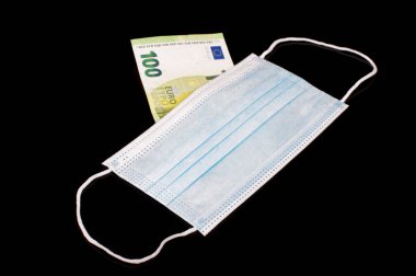 Tıbbi maskenin arkasındaki 100 Euro banknot siyah yansıtıcı arka planda izole edilmiş.