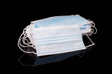 Tıbbi virüs korumalı tek kullanımlık maske yığını siyah yansıtıcı arka planda izole edilmiş.