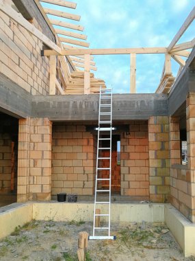 İnşaat alanındaki seramik tuğla duvara yakın alüminyum merdivenler.