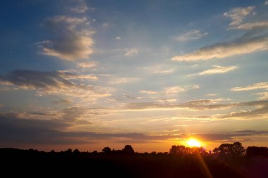 Alan veya çayır üzerinde doğal günbatımı güneş doğuyor. Parlak dramatik gökyüzü ve karanlık yere. Kırsal manzara renkli gökyüzü gün batımında altında şafak Sunrise. Güneş bitti manzarası