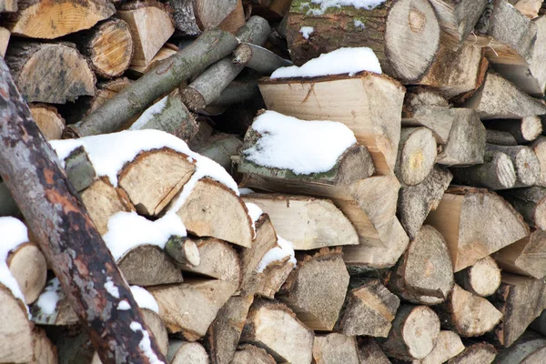 Wood fuel covered with snow. Stacked tree blocks