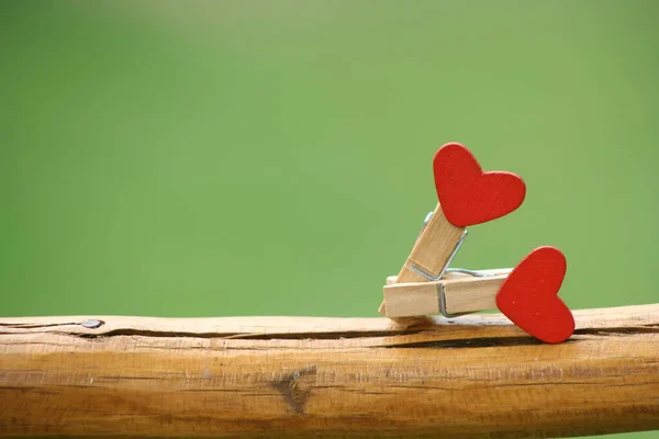 Imitation of sexual position. Clothes pegs reminiscent of having sex. Clothes pegs with red hearts on a green background.