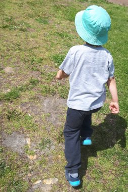 Küçük çocuk açık hava parkında çayırda koşuyor..