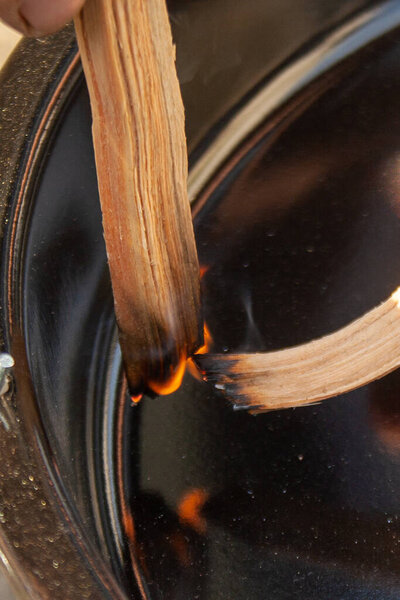 Starting Fire for Charcoal Grill. Arm With Long-Handled Tongs Setting Fire Closeup. Bright Flames and Burning Wood.
