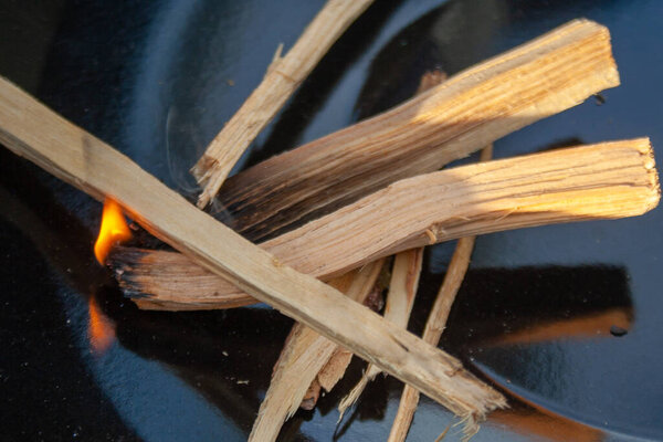 Starting Fire for Charcoal Grill. Arm With Long-Handled Tongs Setting Fire Closeup. Bright Flames and Burning Wood.