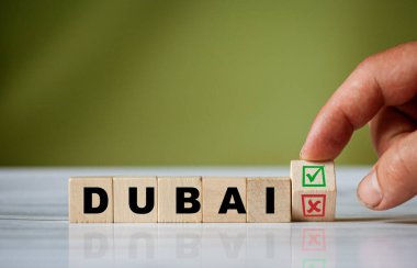 El ahşap küpü çevirir ve DUBAI kelimesini yeşil pozitif işaret kutusu ve kırmızı reddetme X işaretli kutusuyla değiştirir.