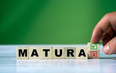 Bu el ahşap küpü çevirir ve yeşil pozitif işaret kutusu ve kırmızı reddetme X işaretli kutusuyla MATURA (İngilizce matura sınavı) Polonyalı sözcüğünü değiştirir..