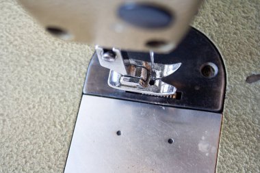 Dikiş makinesi ayak ve iğne. Yaklaş, makro. Metin için boş alan. Kumaş endüstriyel